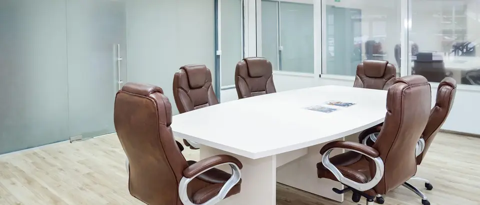 An empty meeting room with a white table and leather chairs