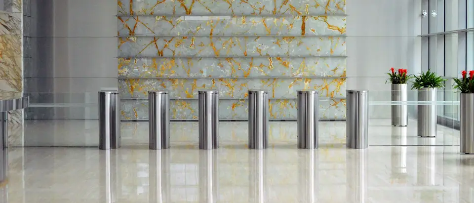A marble office building lobby with steel entry gates and tall windows